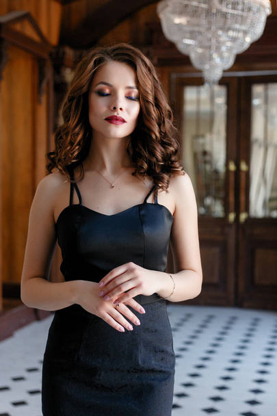 Elegant young woman in black evening dress posing in vintage interior. Fashion shot. - Foto, afbeelding