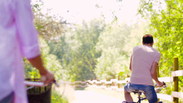 feliz pareja montando bicicletas en el parque de verano
 - Imágenes, Vídeo