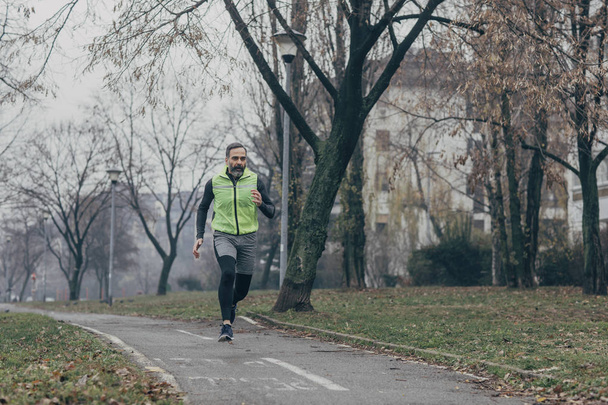 Handsome middle-aged Caucasian man enjoying morning run in the park. - Fotoğraf, Görsel