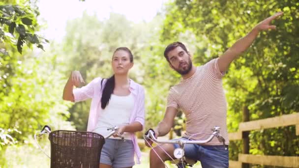 happy couple with bicycles talking at summer park - 映像、動画