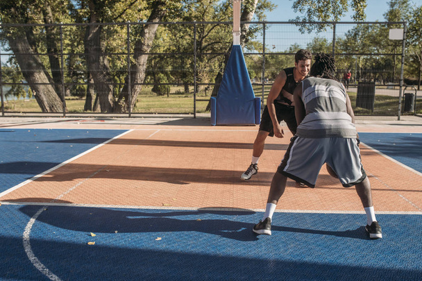 Two man playing basketball at outdoor court. - 写真・画像