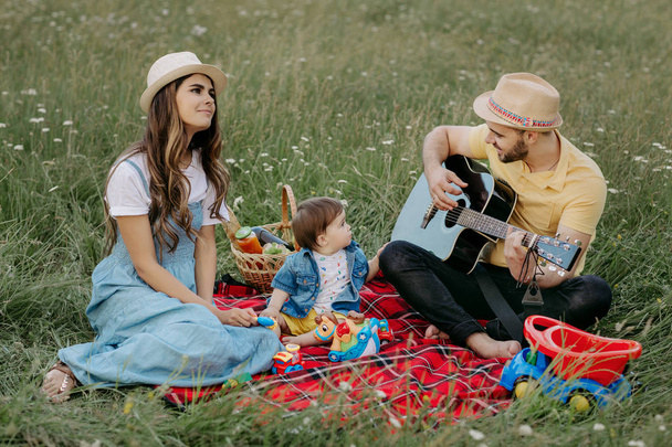 Happy family on a picnic. Dad, mom and son are resting in nature. Music concept. - Fotografie, Obrázek