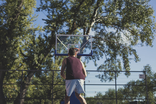 Young Caucasian man training basketball at outdoor court. - Foto, Imagen