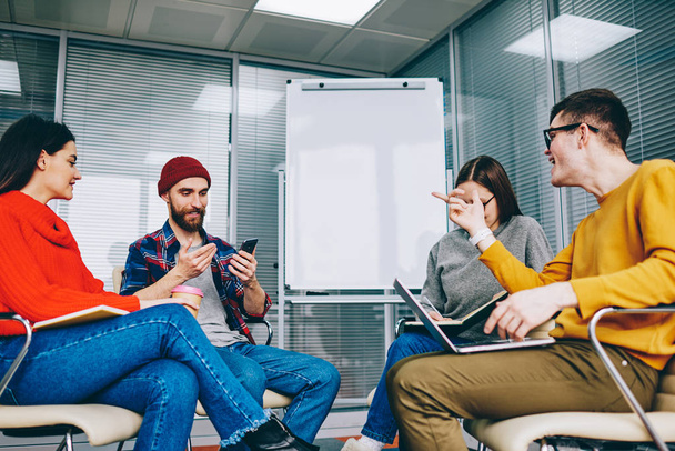 Group of millennial hipster students dressed in casual wear discussing website and app using modern technology and wireless internet during courses in classroom with flip chart with mock up area - Фото, зображення