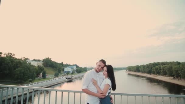 Ένα ζευγάρι ερωτευμένων στέκεται σε μια γέφυρα ενάντια σε ένα καταγάλανο ουρανό. - Πλάνα, βίντεο