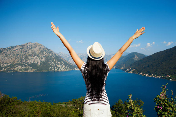 Back view of happy young woman with hands up. Freedom concept. Montenegro. Kotor. - Фото, изображение