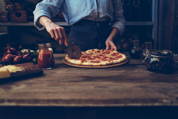 Cook's hands making homemade pizza on the table. Pizza with ingredients. Tomatoes, garlic, parsley, pepper, and parmesan cheese on dark wooden background. Food, family and people concept. - Foto, immagini