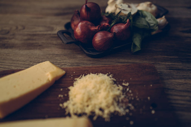 Pizza cooking ingredients. Vegetables, cheese and spices. The ingredients for a recipe for cooking pizza on the dark rustic background. Healthy foods, cooking concept. Toned image. - Photo, Image