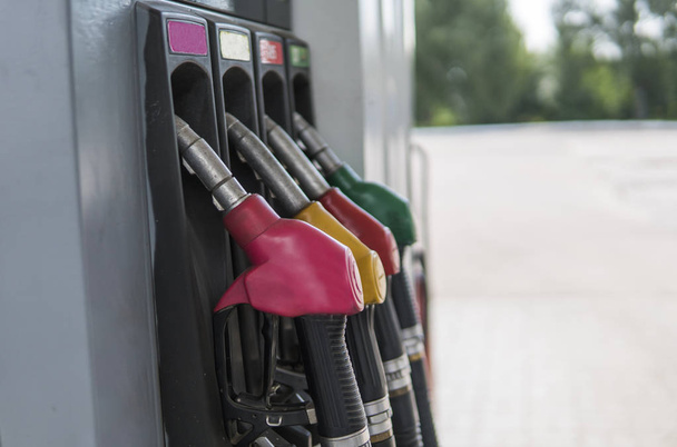Close up on dirty fuel nozzle in oil dispenser with gasoline and diesel in service gas station. Pattern petrol pump gun filling green red yellow pink colorful style. Energy. - Zdjęcie, obraz