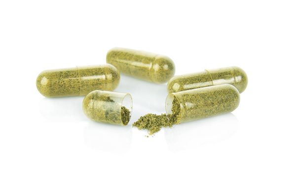 kruid capsule met groene kruiden blad geïsoleerd op witte achtergrond - Foto, afbeelding