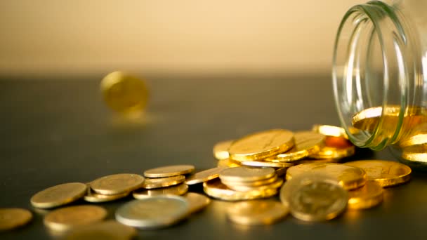 Крупним планом натюрморт з золотими монетами на чорному столі і обертається копійки. Жовті монети випали з банки
. - Кадри, відео