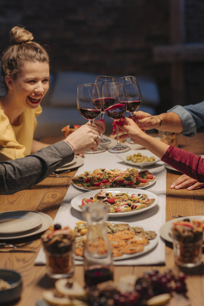 Group of friends toasting with wine glasses at home celebration. - Valokuva, kuva