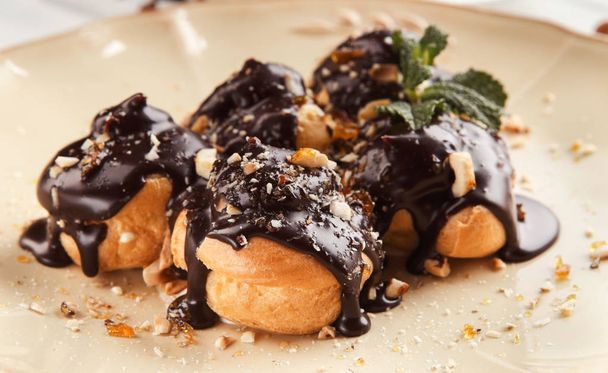French profitroles with chocolate icing and mint leaves - Photo, Image