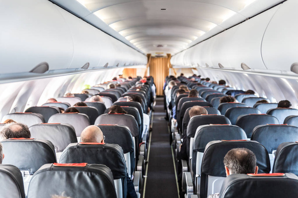 飛行中に自分の席の乗客が付いている商業飛行機のインテリア. - 写真・画像