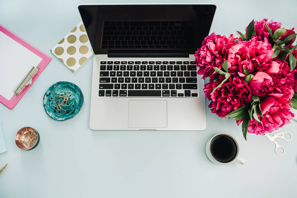 Espaço de trabalho com laptop e buquê de flores de peônia rosa no fundo azul. Flat lay, vista superior home office desk
. - Foto, Imagem