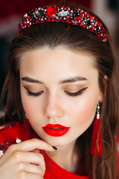 Bruneta žena v červené barvě s profesionálního make-upu dotýkání obličeje. - Fotografie, Obrázek