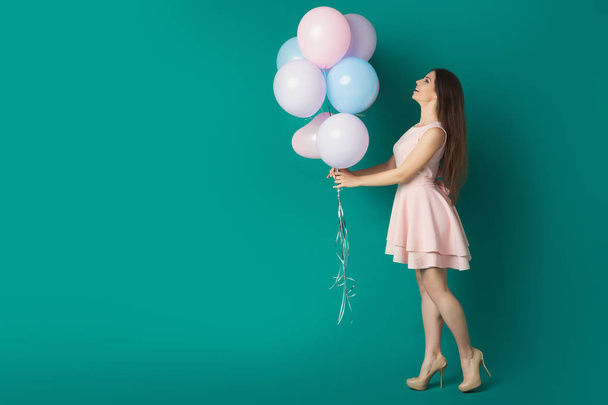 Счастливая девушка держит воздушные шары на голубом фоне студии
 - Фото, изображение