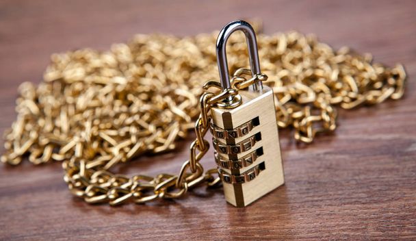cadenas en laiton avec une chaîne en or sur un fond en bois close up
 - Photo, image