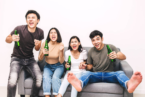 Группа друзей пьет пиво вместе и смотрит футбол на диване в домашних условиях.
 - Фото, изображение