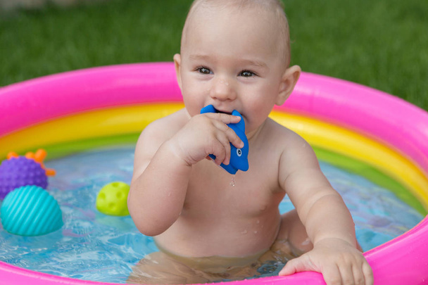 Un bambino piccolo sta facendo il bagno in una piscina, piscina gonfiabile per bambini gonfiabile in estate - Foto, immagini