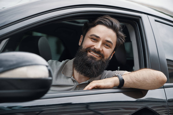 Jonge man die lacht tijdens het rijden van een auto - Foto, afbeelding