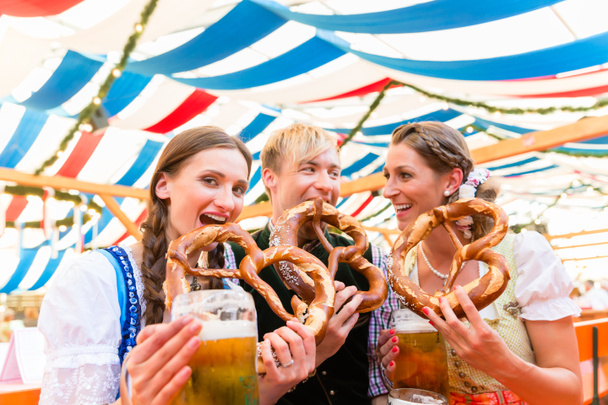 Vrienden reus pretzels eten en drinken in bier tent - Foto, afbeelding