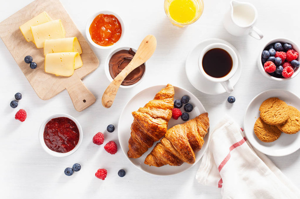 Continentaal ontbijt met croissant, jam, chocopasta en koffie. Bovenaanzicht - Foto, afbeelding