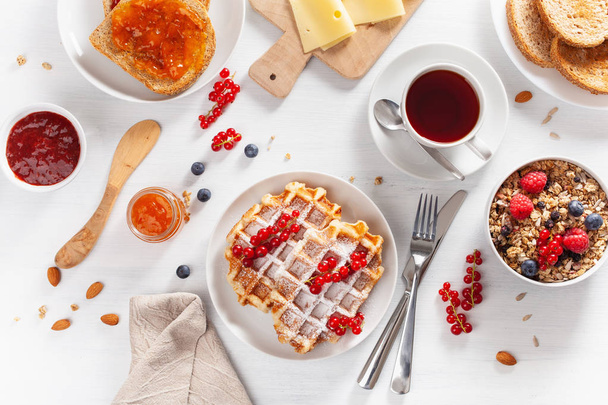 granola berry dió, gofri, pirítós, lekvár és tea a reggeli. Szemközti nézet - Fotó, kép