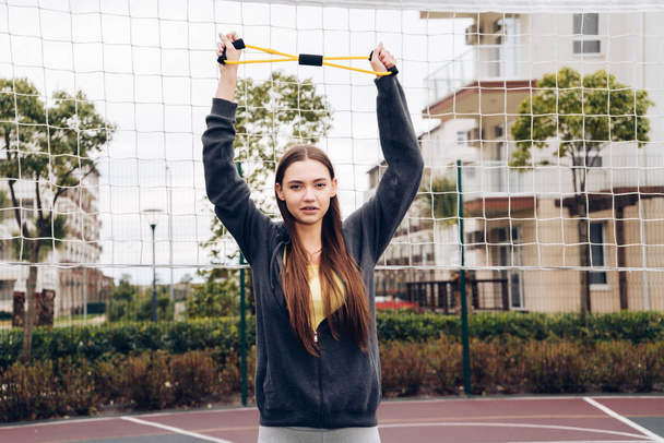 confiado chica delgada hace ejercicios para las manos en el campo de deportes, lleva un estilo de vida activo
 - Foto, Imagen