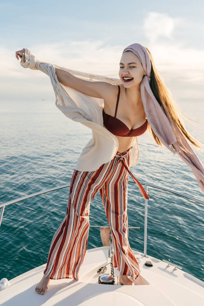 a luxurious young girl in summer stylish clothes rests on her yacht, enjoys sea voyage - Photo, Image