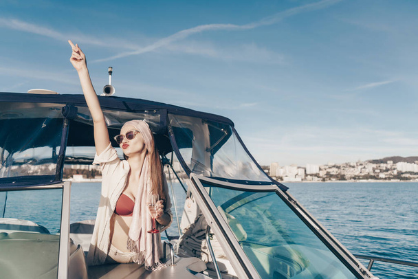 a gorgeous gay girl in sunglasses swims the Caribbean sea on her yacht, drinks champagne - Фото, зображення