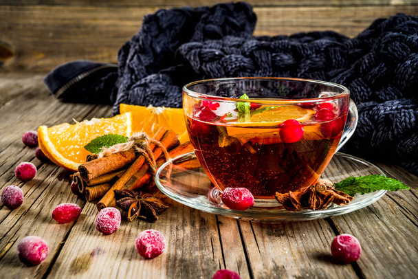 Φθινόπωρο-Χειμώνας ζεστό ρόφημα, cranberry πικάντικο τσάι με κανέλα, πορτοκάλι και γλυκάνισο. Σε ένα παλιό ξύλινο φόντο, με μια ζεστή κουβέρτα, αντιγράψτε χώρο για το κείμενο - Φωτογραφία, εικόνα