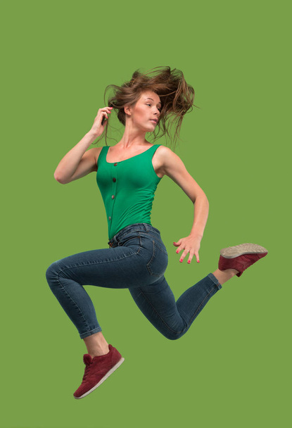 Freedom in moving. Pretty young woman jumping against orange background - Foto, imagen