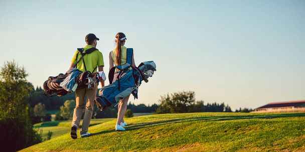 Szczęśliwa para podczas noszenia na sobie stroje golf stoją worki - Zdjęcie, obraz