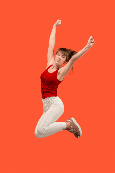 Freedom in moving. Pretty young woman jumping against orange background - 写真・画像