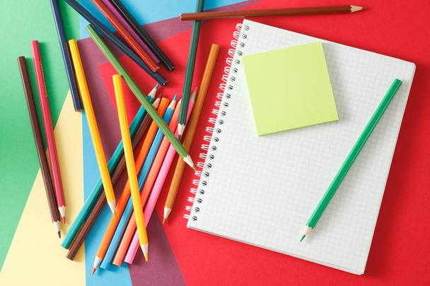 Notebook and pencils lie on colored paper.  - Foto, Imagem