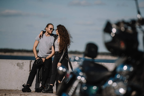 selective focus of young couple hugging on quay with motorcycle on foreground - Photo, Image
