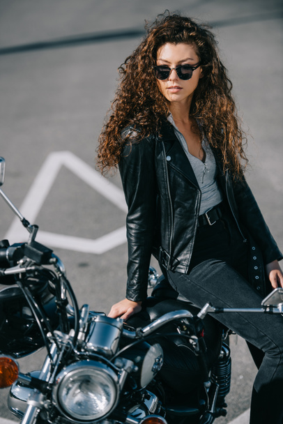 bela mulher em óculos de sol sentado em moto vintage no estacionamento
 - Foto, Imagem