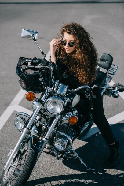 beautiful female biker sitting on motorbike on parking  - 写真・画像