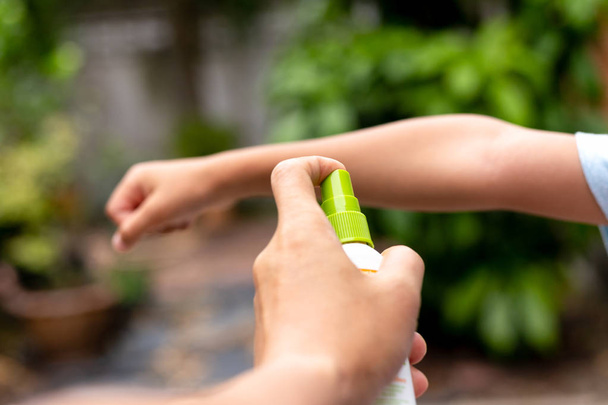 Vater sprüht seinem Sohn im Garten Insektenschutzmittel auf den Arm. - Foto, Bild