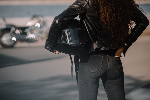 cropped view of woman holding helmet, motorcycle standing on background - Foto, imagen