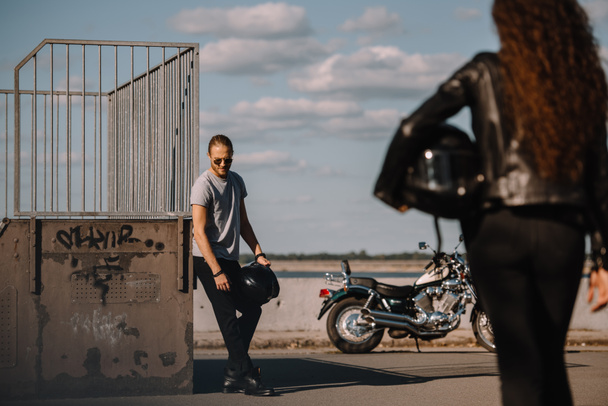 girl holding helmet and going to boyfriend with vintage motorbike  - Foto, Imagen
