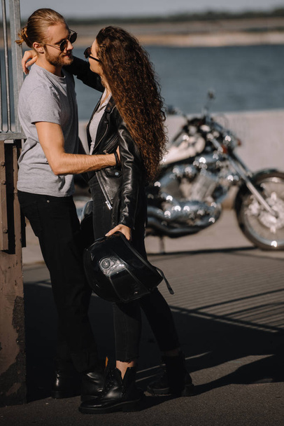 woman and man embracing in city with motorbike on background - Fotó, kép