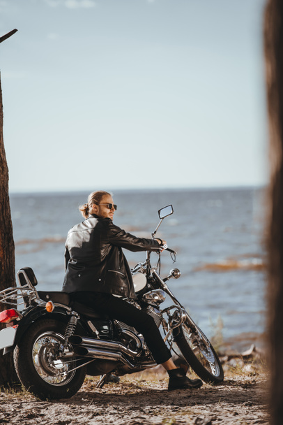 a fekete bőr kabát ül chopper motorkerékpár a tenger közelében motoros - Fotó, kép