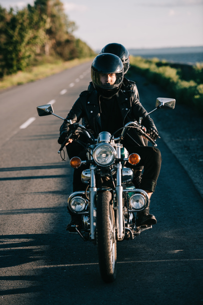 jovem casal em capacetes montando motocicleta clássica na estrada do país
 - Foto, Imagem