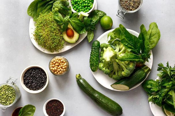 Ingredients source of protein for vegetarians: green peas, cucumber, lucerne, zucchini, spinach, basil, avocado, lime, black beans, black quinoa, chickpeas, green lentils on gray concrete background, top view flat lay - Fotó, kép