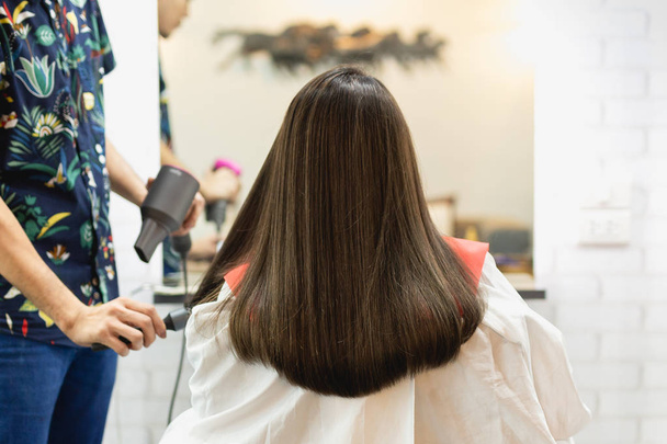 Coiffeur styliste faisant coiffure en utilisant sèche-cheveux soufflant sur les cheveux du client au salon de beauté
. - Photo, image