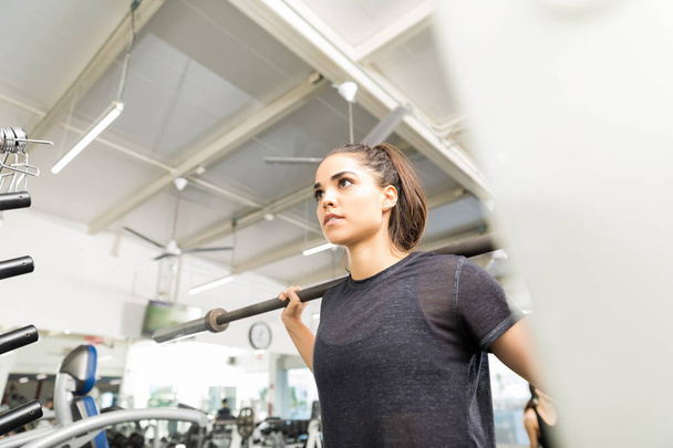Низкий угол зрения спортивной женщины упражнения с пустой штангой в тренажерном зале
 - Фото, изображение
