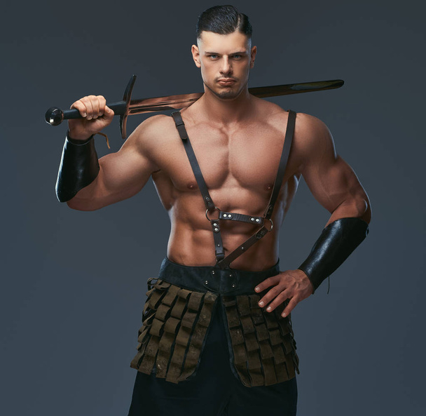 Brutal guerrier de la Grèce antique avec un corps musclé en uniforme de combat posant sur un fond sombre
 - Photo, image