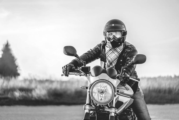 Monochrome photo of biker on sport motorcycle on road - 写真・画像